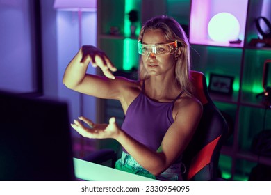 Young blonde woman streamer playing video game using virtual reality glasses at gaming room - Powered by Shutterstock