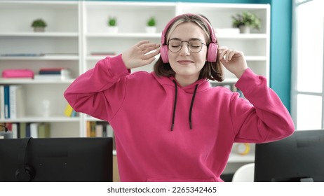 Young blonde woman student smiling confident listening to music and dancing at library university - Powered by Shutterstock