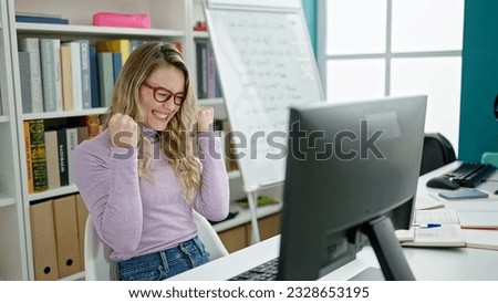 Young blonde woman student using computer with winner expression at classroom