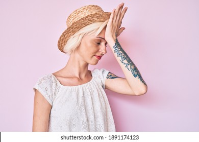 Young Blonde Woman With Tattoo Wearing Summer Hat Surprised With Hand On Head For Mistake, Remember Error. Forgot, Bad Memory Concept. 