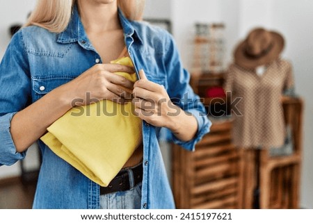 Young blonde woman thief stealing handbag at clothing store