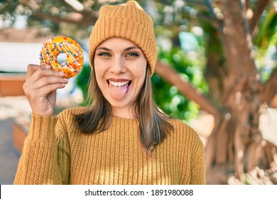 Young blonde woman with tongue out holding donut at the park. - Powered by Shutterstock