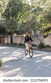 Young Blonde Woman In Trendy Outfit Riding Bicycle On Sunny Street In Turkey