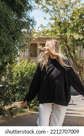 Young Blonde Woman In Trendy Outfit Smiling While Walking On Street In Turkey