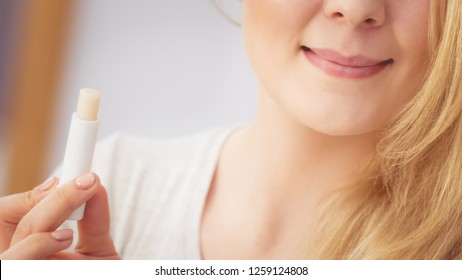 Young Blonde Woman Using Lip Balm On Her Lips. Body Care And Beauty Concept.