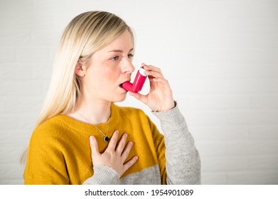 Young Blonde Woman Using A Red Asthma Spray Inhaler