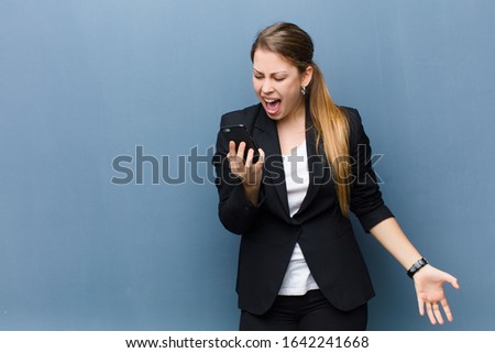 young blonde woman using a smartphone against grunge wall background
