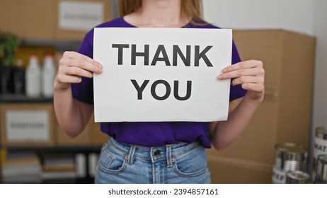 Young blonde woman volunteer holding thank you message at charity center