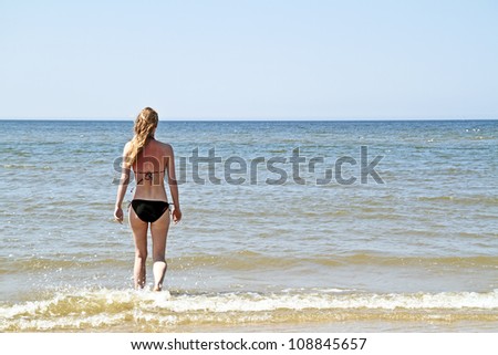 Young blonde woman walking into the ocean
