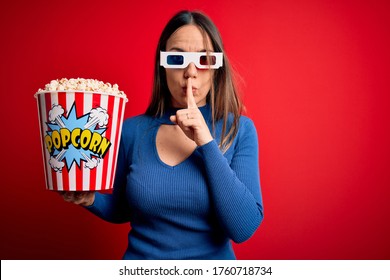 Young Blonde Woman Wearing 3d Glasses And Eating Pack Of Popcorn Watching A Movie On Cinema Asking To Be Quiet With Finger On Lips. Silence And Secret Concept.