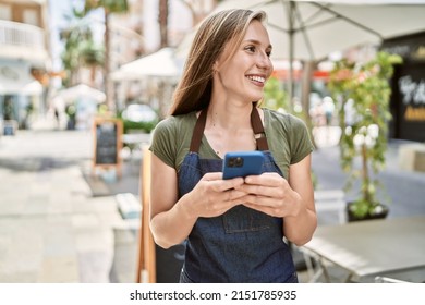 Young blonde woman wearing apron using smartphone at coffee shop - Powered by Shutterstock