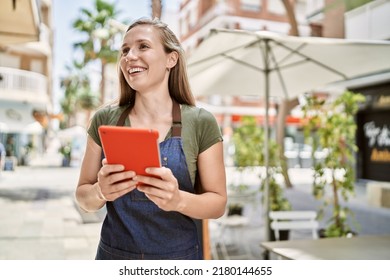 Young blonde woman wearing apron using touchpad at coffee shop - Powered by Shutterstock