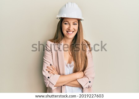 Young blonde woman wearing architect hardhat smiling and laughing hard out loud because funny crazy joke. 