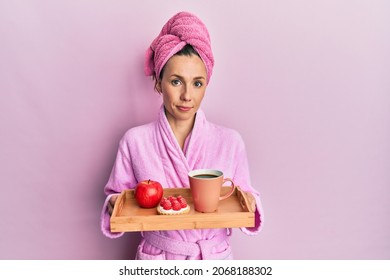 Young blonde woman wearing bathrobe holding tray with breakfast relaxed with serious expression on face. simple and natural looking at the camera.  - Powered by Shutterstock