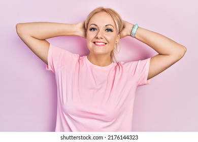 Young Blonde Woman Wearing Casual Pink T Shirt Relaxing And Stretching, Arms And Hands Behind Head And Neck Smiling Happy 