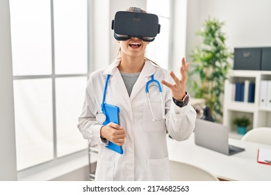 Young Blonde Woman Wearing Doctor Uniform Using Touchpad And Vr Goggles At Clinic