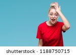 Young blonde woman wearing glasses over isolated background surprised with hand on head for mistake, remember error. Forgot, bad memory concept.