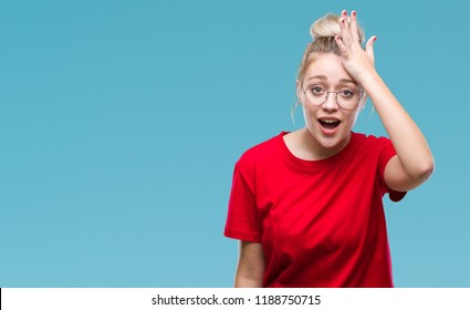 Young blonde woman wearing glasses over isolated background surprised with hand on head for mistake, remember error. Forgot, bad memory concept.