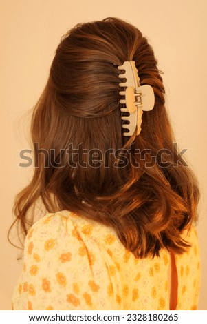 Young blonde woman wearing hair up in claw clip. Summer hairstyle. Trendy hairstyle. Yellow summer dress. Beige claw clip. 