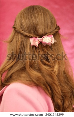 Young blonde woman wearing pink hair bow for Valentines Day. Trendy 2023-2024 hairstyle. Pretty in pink. 