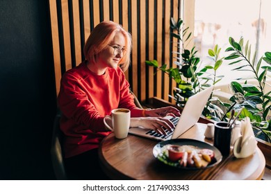 Young Blonde Woman Wearing Red Casual Sweater In Cafe Working On The Laptop Computer And Drinking Coffe Lifestyle