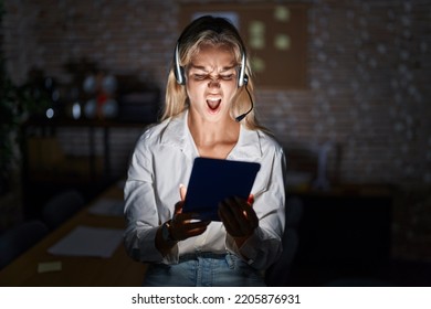 Young Blonde Woman Working At The Office At Night Angry And Mad Screaming Frustrated And Furious, Shouting With Anger. Rage And Aggressive Concept. 