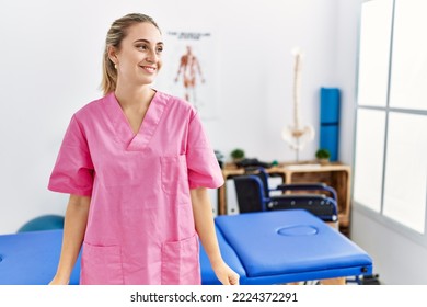 Young Blonde Woman Working At Pain Recovery Clinic Looking Away To Side With Smile On Face, Natural Expression. Laughing Confident. 