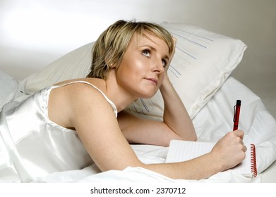 Young Blondie Woman Writing A Journal In Bed