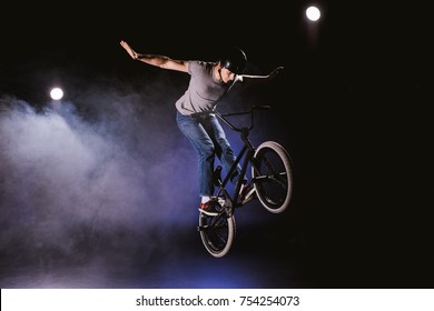 young bmx cyclist in helmet performing stunt and jumping with bicycle in smoke - Powered by Shutterstock