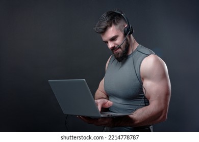 Young Bodybuilder, Online Fitness Coach, Using A Laptop And A Headset To Talk To An Online Client, Studio Image