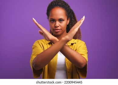 Young Bold Attractive African American Woman Makes Stop Gesture Crossing Hands In Front Of Him Calls To Rein Up Or Prohibit Violation Of Personal Boundaries Stands On Purple Background In Studio