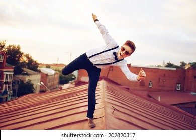 Young bold girl woman in hipster clothes, jumping on the roof, dressed like a boy man in a shirt, bow-tie, suspenders and pants trousers - Powered by Shutterstock