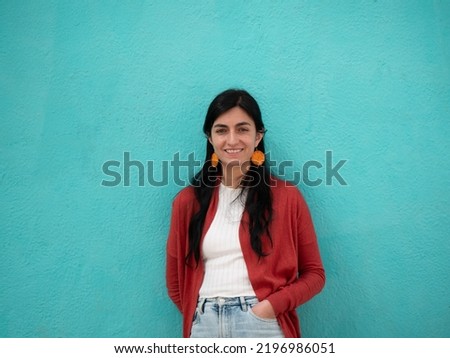 Young Bolivian Woman Poses Looking at the Camera Against a Turquoise Wall