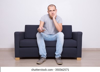 Young Bored Man Sitting On Sofa And Watching Tv At Home