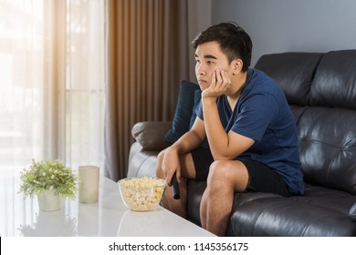 Young Bored Man Watching Tv And Sitting On Sofa In The Living Room