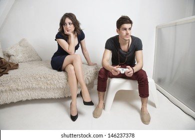 Young Bored Woman Sitting On Sofa With Man Playing Video Game