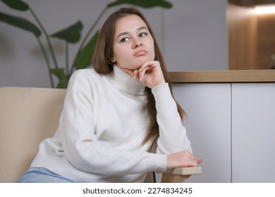 Young bored woman teenager sitting in armchair at home, sad upset frustrated girl - Shutterstock ID 2274834245