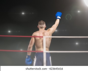 Young boxer raising hand after victory on black background - Powered by Shutterstock