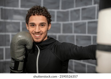 Young boxer smiling while training with a punching bag in the gym, showcasing skill and determination in boxing gloves