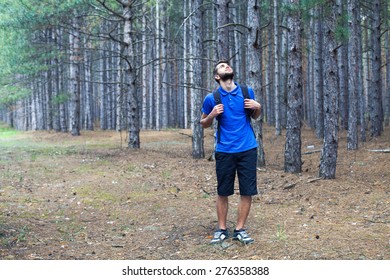 The young boy with a backpack stand in forest