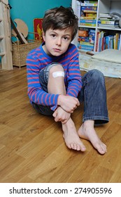 Young Boy With Band Aid On His Knee Is Holding His Leg