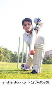 Young Boy Batting In Protective Gear During A Cricket