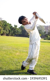 Young Boy Batting In Protective Gear During A Cricket