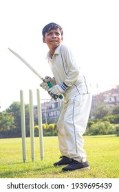 Young Boy Batting In Protective Gear During A Cricket