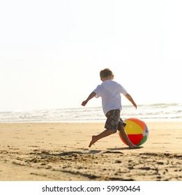 Young Boy At The Beach Plays With A Big Beachball