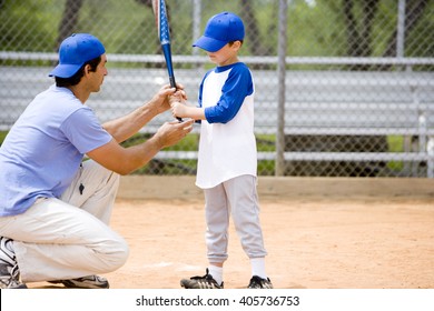 Young boy being shown how to bat in baseball