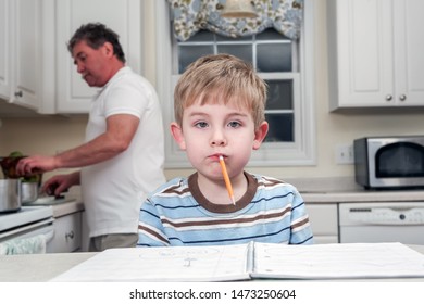 Young Boy Being Silly With Pencil In His Mouth, Distracted While Doing Homework