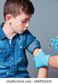 Young boy being vaccinated by a b¡nurse or doctor, isolated on grey background, covid-19 or coronavirus vaccination concept
