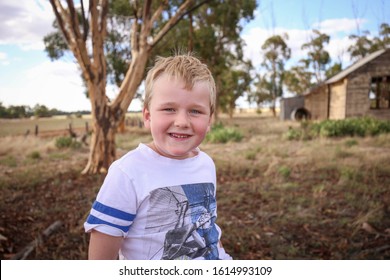 Young Boy With Big Happy Smile In Front Of Old Run Down Abandoned School In Central Victoria, Australia