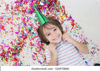 Young boy blows out confetti, isolated on white background